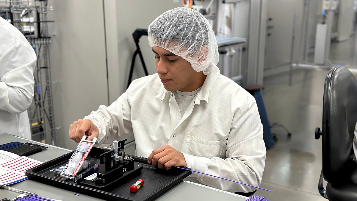 AuST technician assembling catheter components at a cleanroom workstation